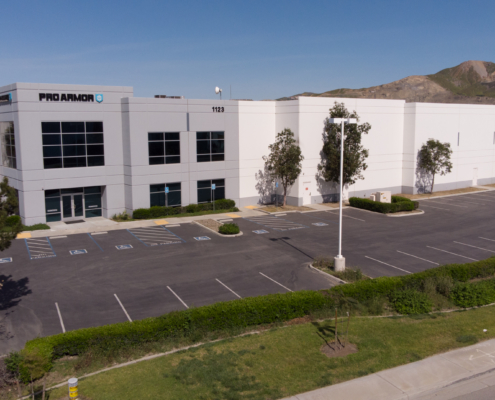 Large industrial building with Proarmour sign and mountains in the background